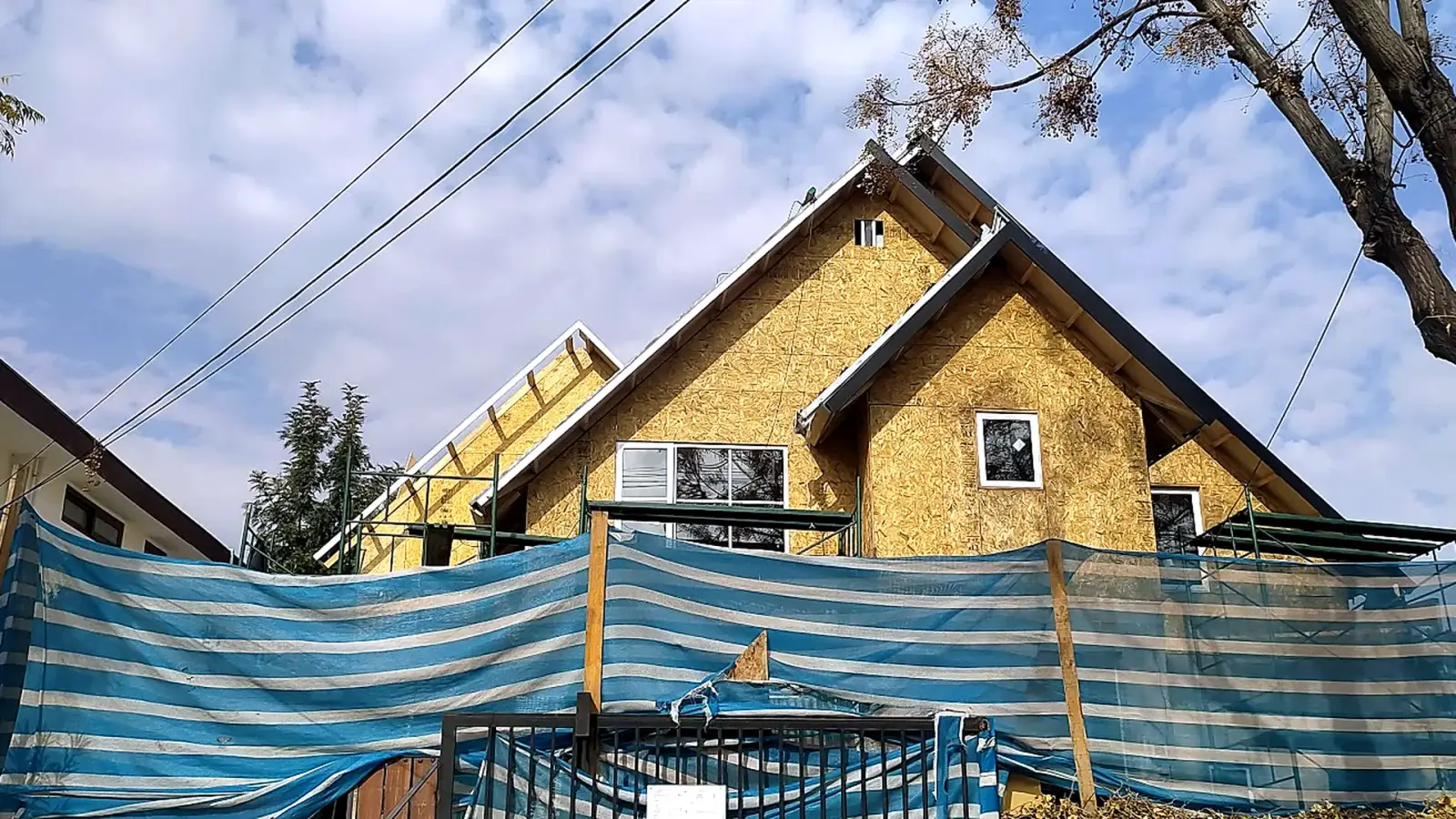 Casa en construcción de Construcasa: fachada revestida en paneles OSB con techumbre a dos aguas y ventanas instaladas.