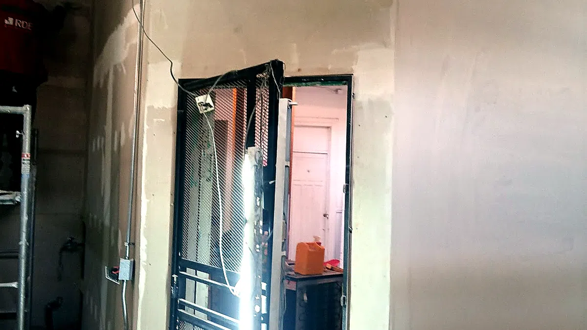 Interior de una casa en remodelación: muros estucados, puerta nueva e instalaciones eléctricas a la vista.